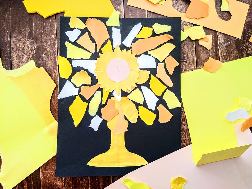 Black paper with a golden Monstrance made out of a collage of torn paper scraps in yellow and white.