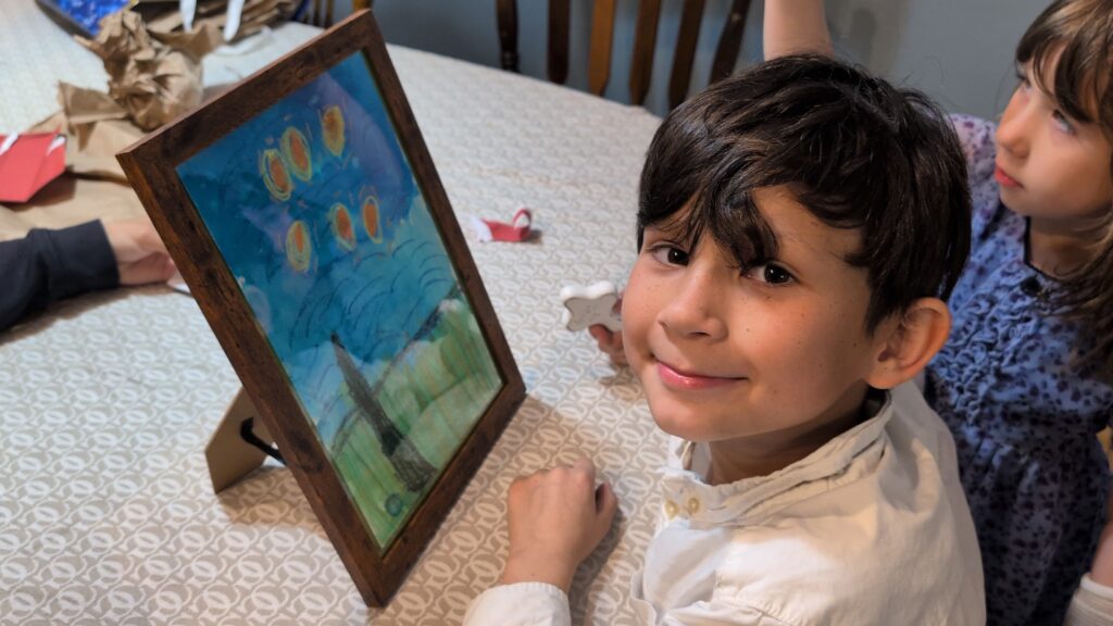 image of child smiling with a painting in front of him